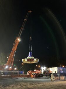 Tunnel boring machine cutter head being unloaded at night